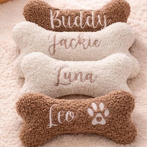 Può includere: Quattro giocattoli di peluche a forma di osso realizzati in tessuto sherpa testurizzato. Due sono marroni e due sono color crema. Ogni giocattolo è ricamato con un nome in corsivo: Buddy, Jackie, Luna e Leo. Il giocattolo Leo ha un'impronta bianca.