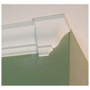 Peut inclure: Un morceau de moulure de couronne blanche installé dans un coin de pièce. La moulure présente un profil décoratif incurvé, placé où le mur rencontre le plafond. Le mur est peint en vert et le plafond est blanc.