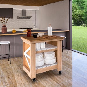 May include: A wooden kitchen cart with two shelves, featuring a white painted design on the front. The cart is loaded with white plates and bowls, and is positioned in a modern kitchen with a large window overlooking a grassy lawn.