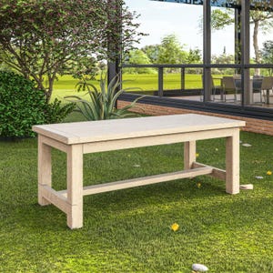 Puede incluir: Una mesa rectangular de exterior de color claro con un diseño de listones. La mesa es de madera y mide aproximadamente 152 cm de largo. Está colocada sobre un césped verde con árboles y un edificio con paredes de cristal.