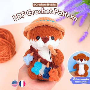 May include: A plush crochet otter toy wearing a tan hat and a brown strap with small colorful fish charms. The text PDF Crochet Pattern is displayed above the otter, and a small circular inset shows the otter without accessories.