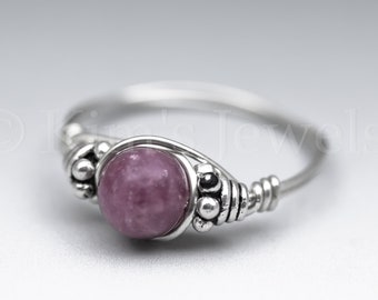 May include: A silver ring with a pink and white gemstone set in a wire-wrapped design.