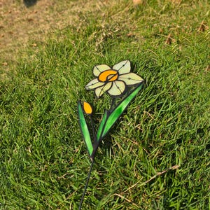 Stained glass daffodil standing upright on grass – garden decoration for spring celebration.