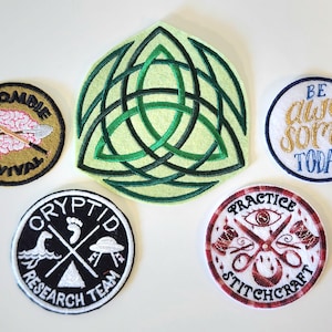 May include: Five embroidered patches: a round Zombie Survival patch with a brain and shovel, a large green Celtic knot, a round Be Awesome Today patch, a round Cryptid Research Team patch with icons, and a round Practice Stitchcraft patch.