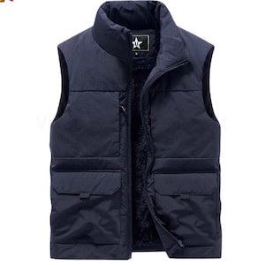 Può includere: Un giubbotto imbottito senza maniche blu navy con chiusura a zip e due grandi tasche sul davanti. Il giubbotto è foderato in pile e ha un colletto alto.