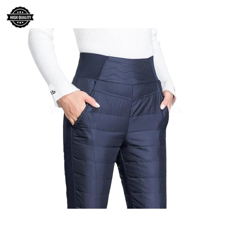 Pode incluir: Cal&ccedil;as acolchoadas azul marinho com cintura alta e bolsos. As cal&ccedil;as t&ecirc;m um padr&atilde;o geom&eacute;trico e uma silhueta ajustada. A modelo est&aacute; vestindo uma camisa branca de manga comprida. As cal&ccedil;as s&atilde;o projetadas para o frio.