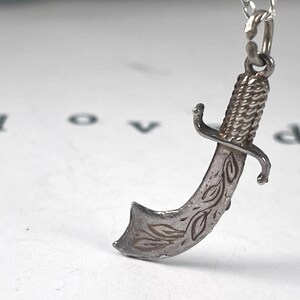 Vintage Sterling Silver Scimitar / Dagger / Knife / Sword Charm
beautifully detailed blade with engraved accents  textured handle. strength protection. strength, bravery, honour, chivalry, warrior spirit.   justice, power, defence of beliefs.