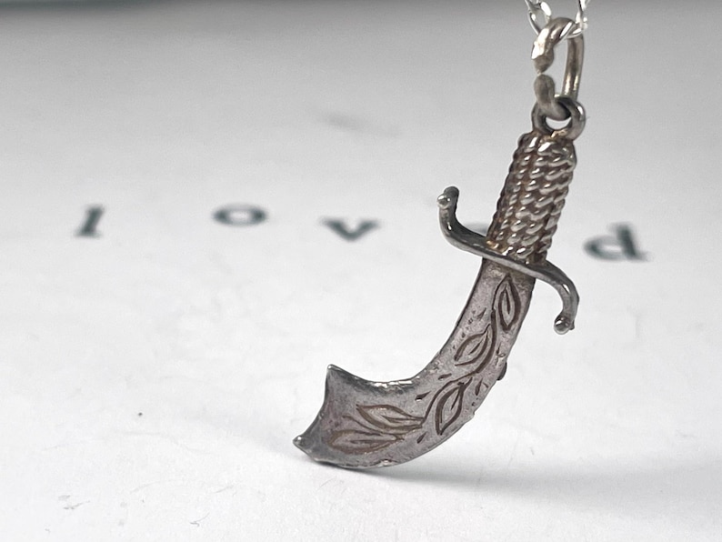 Vintage Sterling Silver Scimitar / Dagger / Knife / Sword Charm
beautifully detailed blade with engraved accents  textured handle. strength protection. strength, bravery, honour, chivalry, warrior spirit.   justice, power, defence of beliefs.