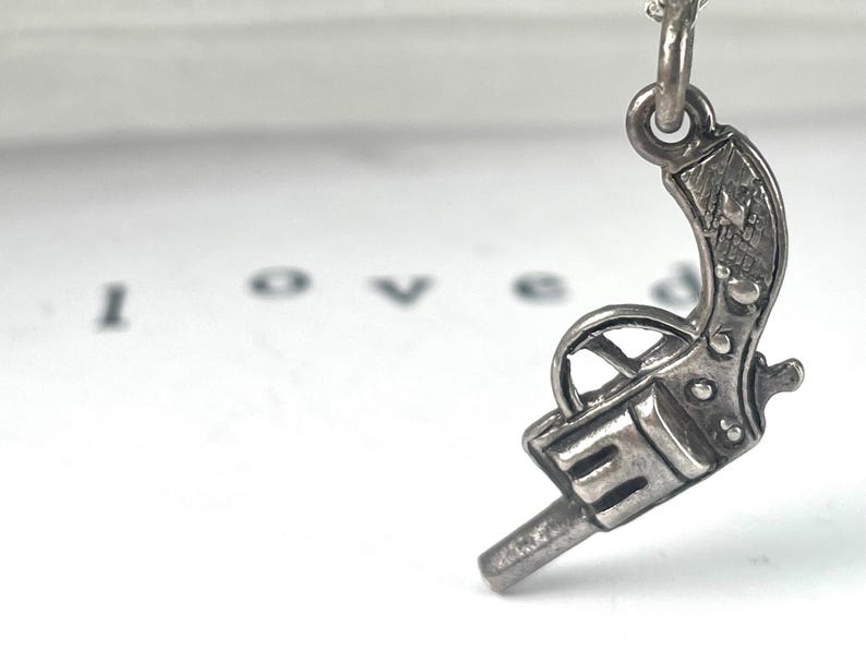 Vintage Miniature Sterling Silver Revolver gun charm intricate details of a classic firearm, with a textured grip and barrel.  Its antique look Western-themed jewellery or for fans of vintage weaponry. miniature silver pistol, cowboy charm, cowgirl