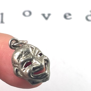 This vintage silver mask charm features the expressive details of a drama mask, symbolizing comedy and tragedy. Its intricate design and timeless patina make it perfect for performing arts lovers or anyone seeking a unique, symbolic jewelry piece.