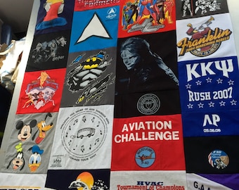 May include: A patchwork quilt made from various t-shirts. The quilt features a variety of designs and logos, including Transformers, Goldberg, Teenage Mutant Ninja Turtles, Franklin, KKY Rush 2007, Aviation Challenge, HVAC Tournament of Champions, and G.A.A. Horne. The quilt is a unique and creative way to display a collection of t-shirts.