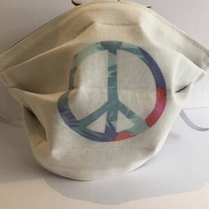 May include: White face mask with a colorful peace sign design. The peace sign is made up of blue, green, purple, and pink colors.