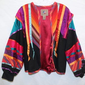 May include: A colorful vintage jacket with a vibrant design. The jacket features a black base with panels of teal, pink, purple, and orange stripes. The interior lining is a deep red. The sleeves have black cuffs.