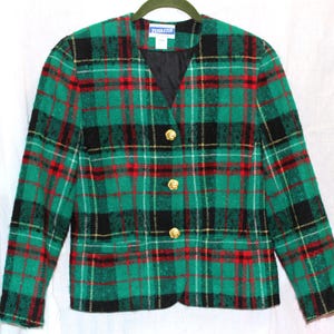 Puede incluir: Un blazer a cuadros verdes, negros y rojos con botones dorados. El blazer tiene cuello en V y mangas largas. La marca "Pendleton" es visible en la etiqueta.