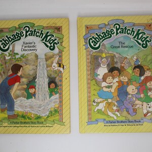 Puede incluir: Dos libros de cuentos vintage de Cabbage Patch Kids. Un libro presenta a un niño con overoles cerca de una cascada, titulado "Xavier's Fantastic Discovery". El otro libro, "The Great Rescue", muestra a un grupo de niños. Ambos libros tienen cubiertas amarillas.