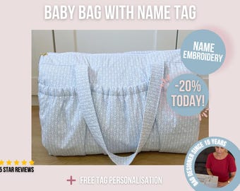 May include: A light blue and white patterned baby bag with a name tag. The bag has two handles and multiple pockets. Text on the image says "BABY BAG WITH NAME TAG", "NAME EMBROIDERY", and "-20% TODAY!".