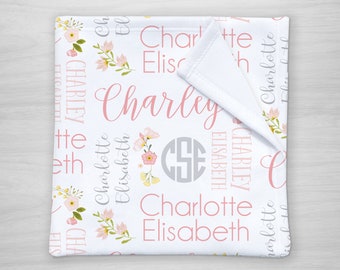 May include: White baby blanket with pink floral designs and the name "Charlotte Elisabeth" repeated throughout. The blanket also features a monogram with the initials "CSE" in a gray circle.