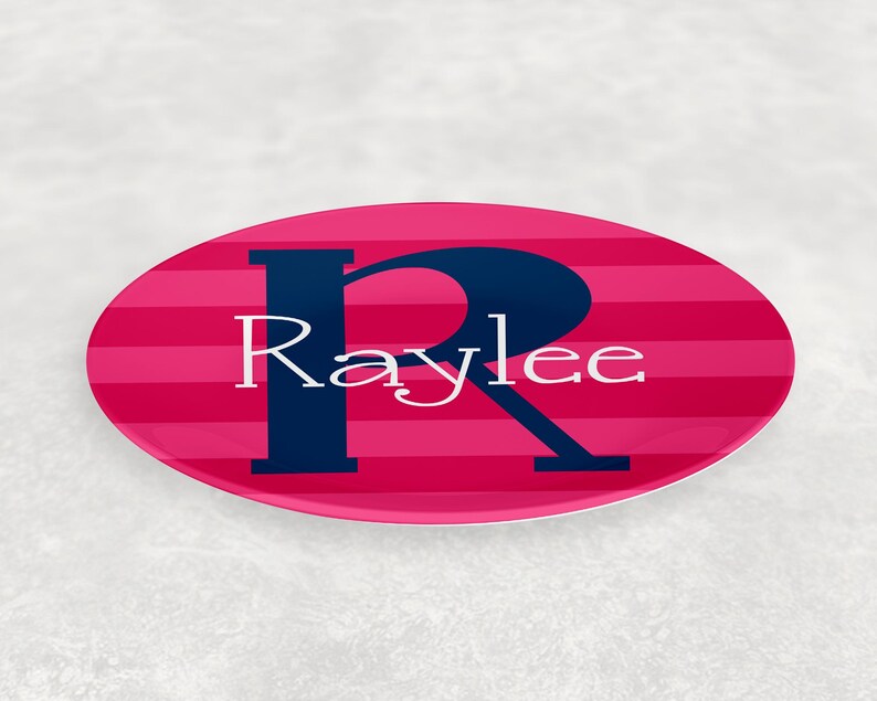 May include: Pink and blue oval plate with white stripes and a large blue letter "R" with the name "Raylee" written in white.