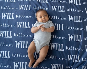 May include: A baby boy lying on a blue blanket with the name "WILL" repeated in white text.
