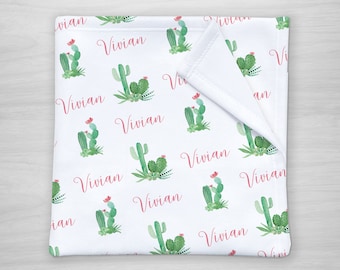 May include: White baby blanket with a repeating pattern of green cactus plants and pink "Vivian" text.