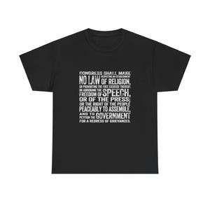 May include: Black t-shirt with white text that reads "Congress shall make no law respecting an establishment of religion, or prohibiting the free exercise thereof: freedom of speech, or of the press; or the right of the people peaceably to assemble, and to petition the government for a redress of grievances."
