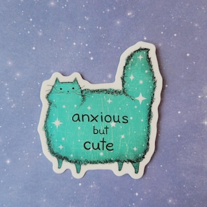 以下が含まれることがあります： 水色の猫のイラストと「anxious but cute」の文字が入ったステッカー。猫は星のアクセントと白い輪郭を持つふわふわの体を持っています。背景は、白い星の詳細を持つ薄紫です。