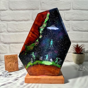 May include: A custom lamp with a galaxy design and green alien figurines. The lamp base is made of wood and has a red glow. The lamp is lit and the galaxy design is visible.