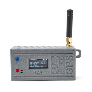 May include: A gray GPS device with a black antenna and a small screen displaying data. The device has a red and blue button, and the text "V4" is visible. The word "GPS" is printed on the side.