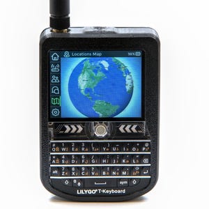 Puede incluir: Dispositivo LILYGO T-Keyboard negro con una pantalla que muestra un mapa del mundo. El dispositivo tiene un teclado QWERTY completo, una pequeña antena y el texto "Locations Map" en la pantalla. La pantalla muestra un 98% de batería.