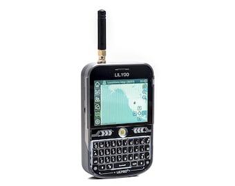 May include: A black and silver LILYGO handheld device with a screen displaying a map. It has a full keyboard, an antenna, and the text "LILYGO" is visible. The screen shows a map with icons and a battery indicator.