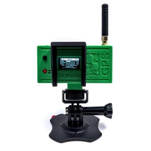 May include: A green GPS device with a black antenna and a small screen displaying data. The device is mounted on a black stand with a GoPro-style mount. The text "V4 Mobile GPS" is visible on the screen.
