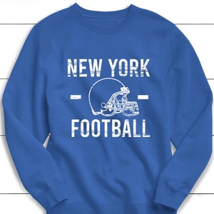 May include: A royal blue sweatshirt with the text "NEW YORK FOOTBALL" in white with a white football helmet graphic.