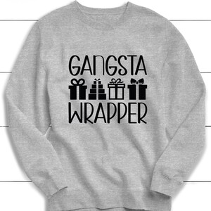 Könnte beinhalten: Ein graues Sweatshirt mit dem Text "Gangsta Wrapper" in schwarzen Buchstaben. Der Text ist von einer Grafik mit vier Geschenkboxen mit Schleifen umgeben.
