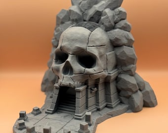 May include: A 3D printed miniature of a skull-shaped temple with a stone entrance and a pathway leading to it. The temple is surrounded by rocks and crystals.