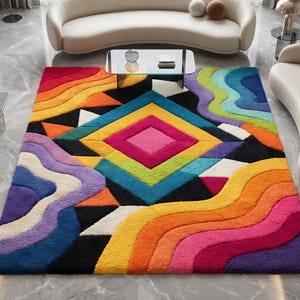May include: A rectangular area rug featuring a vibrant, multi-coloured geometric and wavy pattern. The design includes a central diamond motif in pink, yellow, and blue, surrounded by layered, flowing bands of orange, red, purple, and green.