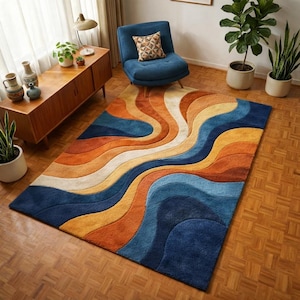 May include: A rectangular rug with a retro design. The rug has a wavy pattern in shades of blue, orange, yellow, and cream. The rug is on a wooden floor, and the room is decorated with mid-century modern furniture.