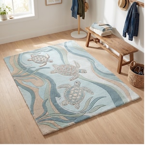 May include: A rectangular area rug featuring a light blue background with three sea turtles in shades of beige and grey. The design includes flowing, wave-like patterns in various tones of blue, teal, and tan, creating a soft, aquatic aesthetic.