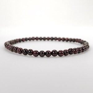 May include: A red garnet gemstone bracelet with small round beads.