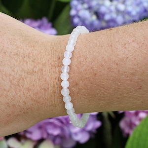 May include: White gemstone bracelet with round beads. The bracelet is made of natural stones and is a beautiful and simple piece of jewelry.