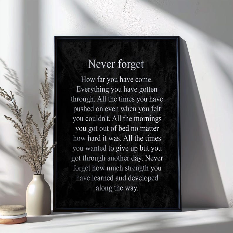 May include: Black and white inspirational quote poster with the text "Never forget" and a message about perseverance and overcoming challenges. The poster has a textured background.