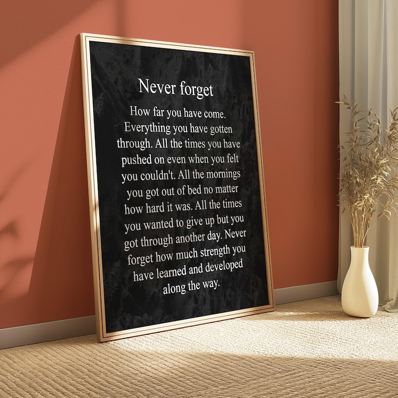 May include: Black and white motivational quote poster with a gold frame. The quote reads "Never forget How far you have come. Everything you have gotten through. All the times you have pushed on even when you felt you couldn't. All the mornings you got out of bed no matter how hard it was. All the times you wanted to give up but you got through another day. Never forget how much strength you have learned and developed along the way."