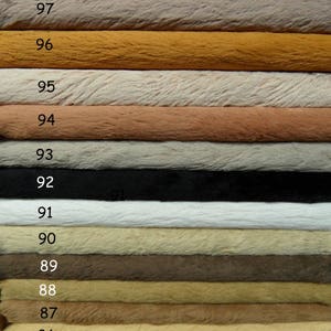 Può includere: Campioni di tessuto in finta pelliccia in vari colori, tra cui marrone, beige, nero e bianco. Ogni campione è numerato da 85 a 98. La pelliccia appare morbida e soffice, con una superficie strutturata.