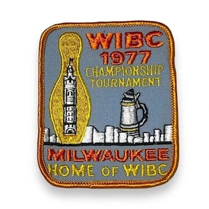 May include: A rectangular embroidered patch with a gray background and a brown border. It features a yellow bowling pin, a silver beer stein, and a white city skyline. Text reads WIBC 1977 CHAMPIONSHIP TOURNAMENT and MILWAUKEE HOME OF WIBC.