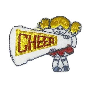 May include: An embroidered patch featuring a figure with yellow hair holding a white megaphone with a yellow banner that has the word CHEER stitched in dark red letters. The figure wears a red skirt and dark blue shoes, outlined in black thread.