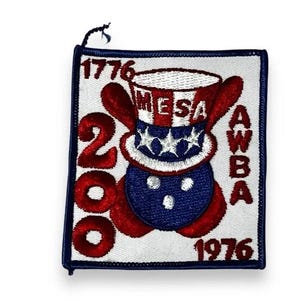 May include: A square embroidered patch with a white background and a dark blue border. The design features a red, white, and blue top hat with the text MESA, surrounded by the numbers 1776, 200, 1976, and the vertical text AWBA in red thread.