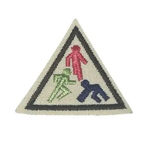 May include: A triangular embroidered patch with a cream-colored background and a thick black border. The design features three stylized human figures in red, green, and dark blue, each depicted in a different pose within the triangular frame.
