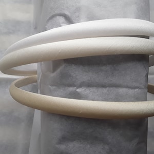 May include: Three white satin headbands, two are white and one is a cream colour.