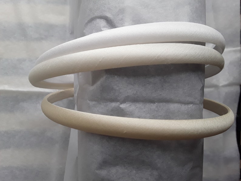 May include: Three white satin headbands, two are white and one is a cream color.