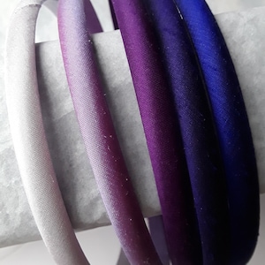 May include: Five fabric headbands in shades of purple, blue, and white. The headbands are ombre, with the color fading from dark to light.