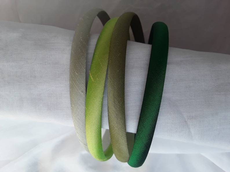 May include: Three satin headbands in shades of green, light green, and gray.